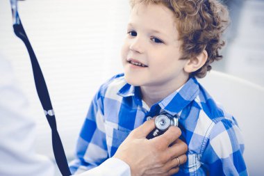 Doktor ve sabırlı çocuk. Doktor küçük çocuğu muayene ediyor. Kliniğe düzenli tıbbi ziyaret. İlaç ve sağlık hizmetleri kavramı