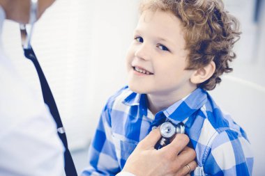 Doktor ve sabırlı çocuk. Doktor küçük çocuğu muayene ediyor. Kliniğe düzenli tıbbi ziyaret. İlaç ve sağlık hizmetleri kavramı