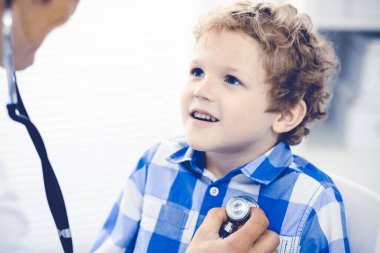 Doktor ve sabırlı çocuk. Doktor küçük çocuğu muayene ediyor. Kliniğe düzenli tıbbi ziyaret. İlaç ve sağlık hizmetleri kavramı
