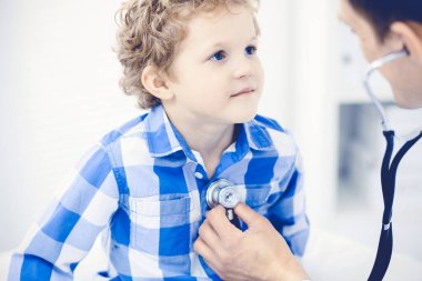 Doktor ve sabırlı çocuk. Doktor küçük çocuğu muayene ediyor. Kliniğe düzenli tıbbi ziyaret. İlaç ve sağlık hizmetleri kavramı
