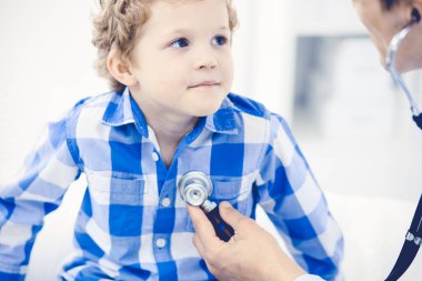 Doktor ve sabırlı çocuk. Doktor küçük çocuğu muayene ediyor. Kliniğe düzenli tıbbi ziyaret. İlaç ve sağlık hizmetleri kavramı