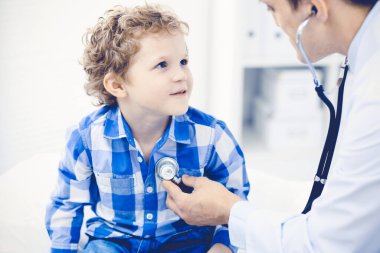 Doktor ve sabırlı çocuk. Doktor küçük çocuğu muayene ediyor. Kliniğe düzenli tıbbi ziyaret. İlaç ve sağlık hizmetleri kavramı