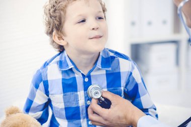 Doktor ve sabırlı çocuk. Doktor küçük çocuğu muayene ediyor. Kliniğe düzenli tıbbi ziyaret. İlaç ve sağlık hizmetleri kavramı
