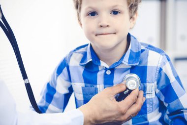 Doktor ve sabırlı çocuk. Doktor küçük çocuğu muayene ediyor. Kliniğe düzenli tıbbi ziyaret. İlaç ve sağlık hizmetleri kavramı