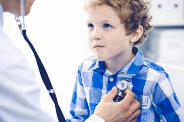 Doktor ve sabırlı çocuk. Doktor küçük çocuğu muayene ediyor. Kliniğe düzenli tıbbi ziyaret. İlaç ve sağlık hizmetleri kavramı