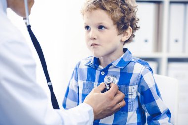 Doktor ve sabırlı çocuk. Doktor küçük çocuğu muayene ediyor. Kliniğe düzenli tıbbi ziyaret. İlaç ve sağlık hizmetleri kavramı