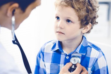 Doktor ve sabırlı çocuk. Doktor küçük çocuğu muayene ediyor. Kliniğe düzenli tıbbi ziyaret. İlaç ve sağlık hizmetleri kavramı