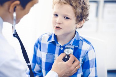 Doktor ve sabırlı çocuk. Doktor küçük çocuğu muayene ediyor. Kliniğe düzenli tıbbi ziyaret. İlaç ve sağlık hizmetleri kavramı