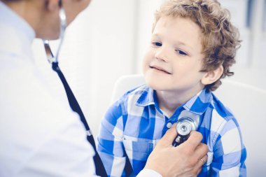 Doktor ve sabırlı çocuk. Doktor küçük çocuğu muayene ediyor. Kliniğe düzenli tıbbi ziyaret. İlaç ve sağlık hizmetleri kavramı