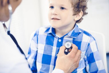 Doktor ve sabırlı çocuk. Doktor küçük çocuğu muayene ediyor. Kliniğe düzenli tıbbi ziyaret. İlaç ve sağlık hizmetleri kavramı