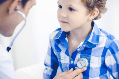 Doktor ve sabırlı çocuk. Doktor küçük çocuğu muayene ediyor. Kliniğe düzenli tıbbi ziyaret. İlaç ve sağlık hizmetleri kavramı