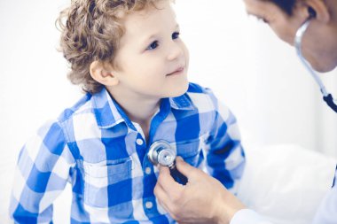 Doktor ve sabırlı çocuk. Doktor küçük çocuğu muayene ediyor. Kliniğe düzenli tıbbi ziyaret. İlaç ve sağlık hizmetleri kavramı
