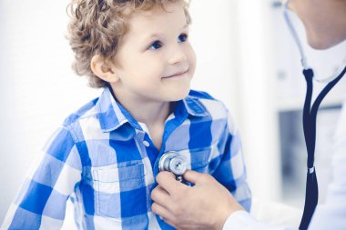 Doktor ve sabırlı çocuk. Doktor küçük çocuğu muayene ediyor. Kliniğe düzenli tıbbi ziyaret. İlaç ve sağlık hizmetleri kavramı
