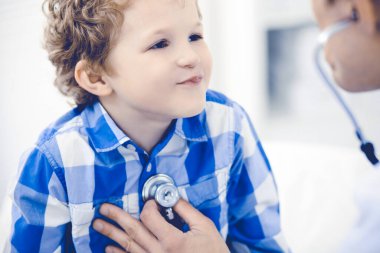 Doktor ve sabırlı çocuk. Doktor küçük çocuğu muayene ediyor. Kliniğe düzenli tıbbi ziyaret. İlaç ve sağlık hizmetleri kavramı