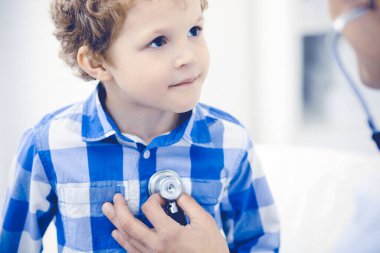 Doktor ve sabırlı çocuk. Doktor küçük çocuğu muayene ediyor. Kliniğe düzenli tıbbi ziyaret. İlaç ve sağlık hizmetleri kavramı