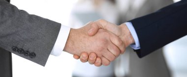 İş adamları toplantıdan ya da pazarlıktan sonra iş arkadaşlarıyla el sıkışıyorlar. Yakın plan. Modern ofisteki bir grup tanınmamış iş adamı ve kadın. Takım çalışması, ortaklık ve tokalaşma