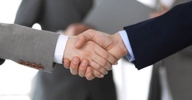 İş adamları toplantıdan ya da pazarlıktan sonra iş arkadaşlarıyla el sıkışıyorlar. Yakın plan. Modern ofisteki bir grup tanınmamış iş adamı ve kadın. Takım çalışması, ortaklık ve tokalaşma