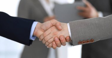 İş adamları toplantıdan ya da pazarlıktan sonra iş arkadaşlarıyla el sıkışıyorlar. Yakın plan. Modern ofisteki bir grup tanınmamış iş adamı ve kadın. Takım çalışması, ortaklık ve tokalaşma