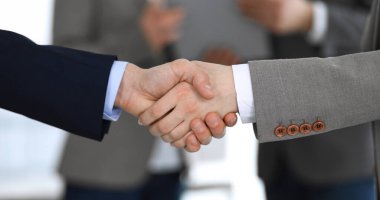 İş adamları toplantıdan ya da pazarlıktan sonra iş arkadaşlarıyla el sıkışıyorlar. Yakın plan. Modern ofisteki bir grup tanınmamış iş adamı ve kadın. Takım çalışması, ortaklık ve tokalaşma