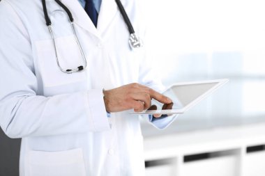Doktor, ağ araştırması ya da sanal hastalık tedavisi için tablet bilgisayar kullanıyor. Eller yakın çekim. Klinikte mükemmel bir tıbbi hizmet. Modern tıp, tıbbi veri ve sağlık hizmetleri kavramları. Ayarlanmış