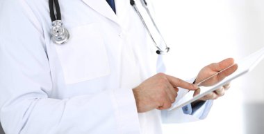 Doktor, ağ araştırması ya da sanal hastalık tedavisi için tablet bilgisayar kullanıyor. Eller yakın çekim. Klinikte mükemmel bir tıbbi hizmet. Modern tıp, tıbbi veri ve sağlık hizmetleri kavramları. Ayarlanmış