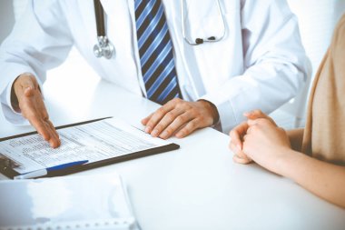 Doktor ve hasta kadın hastane ofisindeki masada bir şey tartışıyorlar. Tıp etiği kavramları ve tıp alanında insanlara yardım