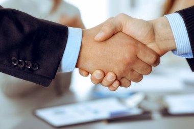 İş arkadaşları alkışlayıp alkışlarken iş adamları toplantıda tokalaşıyor. Modern beyaz ofisteki bir grup tanınmayan iş adamı ve kadın. Başarı takım çalışması, ortaklık ve tokalaşma