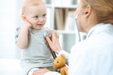 Doktor ve hasta hastanede. Küçük kız steteskopla doktor tarafından muayene ediliyor. Tıp konsepti