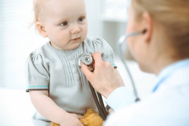 Doktor ve hasta hastanede. Küçük kız steteskopla doktor tarafından muayene ediliyor. Tıp konsepti