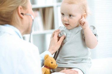 Doktor ve hasta hastanede. Küçük kız steteskopla doktor tarafından muayene ediliyor. Tıp konsepti