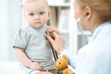 Doktor ve hasta hastanede. Küçük kız steteskopla doktor tarafından muayene ediliyor. Tıp konsepti