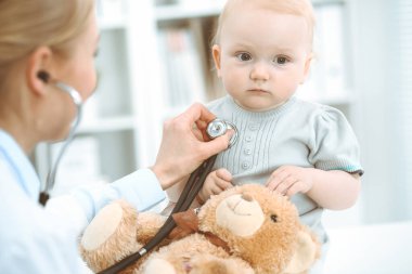 Doktor ve hasta hastanede. Küçük kız steteskopla doktor tarafından muayene ediliyor. Tıp konsepti
