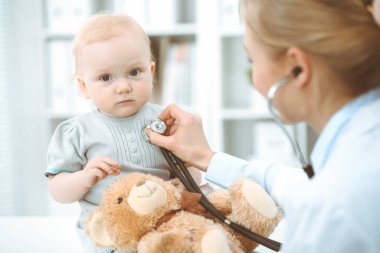 Doktor ve hasta hastanede. Küçük kız steteskopla doktor tarafından muayene ediliyor. Tıp konsepti