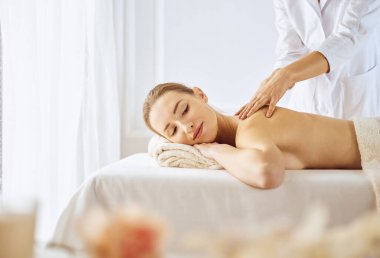 Güzel bir kadın kapalı gözlerle sırt masajından hoşlanıyor. Spa tedavisi kavramı