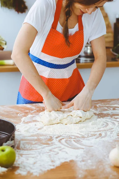 Genç esmer kadın mutfakta pizza ya da el yapımı makarna pişiriyor. Ev hanımı ahşap masada hamur hazırlıyor. Diyet, gıda ve sağlık konsepti