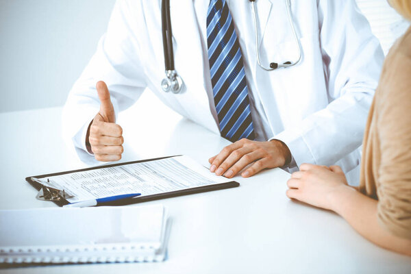 Doctor and patient woman discussing something at the desk in hospital office. Concepts of medical ethics and helping people in medicine