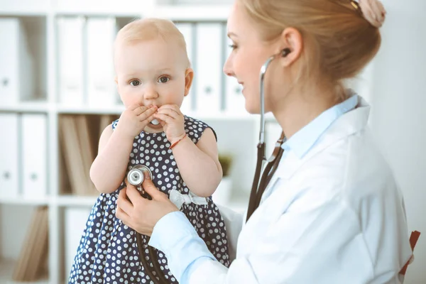 Dokter en patiënt in het ziekenhuis. Meisje gekleed in donkerblauwe jurk in erwten wordt onderzocht door een arts met stethoscoop. Geneesmiddelenconcept — Stockfoto