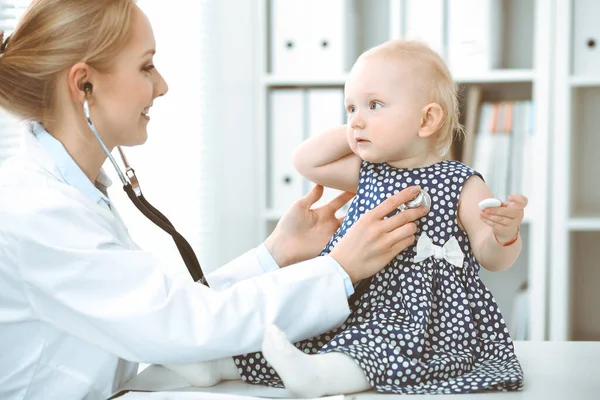Arzt und Patient im Krankenhaus. Kleines Mädchen in dunkelblauem Kleid mit Erbsen wird vom Arzt mit Stethoskop untersucht. Medizinkonzept — Stockfoto