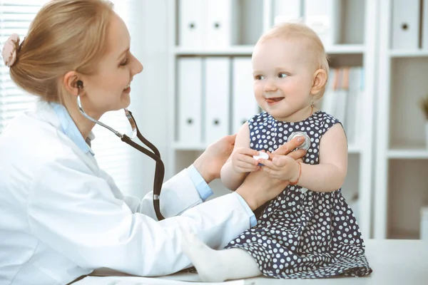 Arzt und Patient im Krankenhaus. Kleines Mädchen in dunkelblauem Kleid mit Erbsen wird vom Arzt mit Stethoskop untersucht. Medizinkonzept — Stockfoto