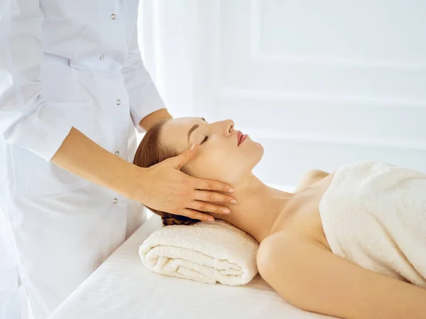 Hermosa mujer disfrutando de masaje facial con los ojos cerrados. Concepto de tratamiento de spa en medicina — Foto de Stock