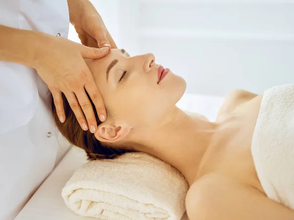 Hermosa mujer disfrutando de masaje facial con los ojos cerrados. Concepto de tratamiento de spa en medicina — Foto de Stock