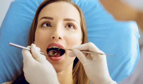 Uśmiechnięta młoda kobieta z nawiasami ortodontycznymi badana przez dentystę w klinice dentystycznej. Zdrowe zęby i koncepcja medycyny — Zdjęcie stockowe