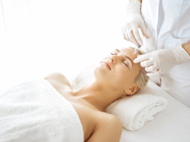 Güzellik uzmanı elleri şırıngayla kadın yüzüne güzellik prosedürü uyguluyor. Kozmetik tıp ve cerrahi, güzellik enjeksiyonları konsepti