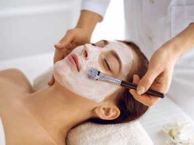 Güzel esmer kadın kapalı gözlerle kozmetik maske takmaktan zevk alıyor. Tıp ve kaplıca merkezi kavramlarında rahatlatıcı tedavi