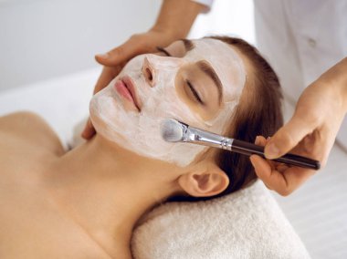 Güzel esmer kadın kapalı gözlerle kozmetik maske takmaktan zevk alıyor. Tıp ve kaplıca merkezi kavramlarında rahatlatıcı tedavi