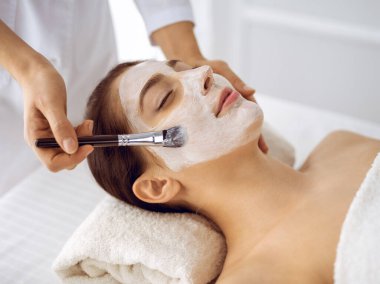 Güzel esmer kadın kapalı gözlerle kozmetik maske takmaktan zevk alıyor. Tıp ve kaplıca merkezi kavramlarında rahatlatıcı tedavi