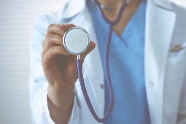 Bilinmeyen doktor kadın steteskop başı tutuyor, yakın plan. Doktor hastayı muayene etmeye ve yardım etmeye hazır. Sağlık hizmetleri, en iyi tedavi ve tıp konseptinde yardım ve sigorta