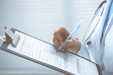 Hastanedeki kadın doktor. Genç kadın doktor hastane ofisinde otururken reçete yazıyor ya da form dolduruyor.