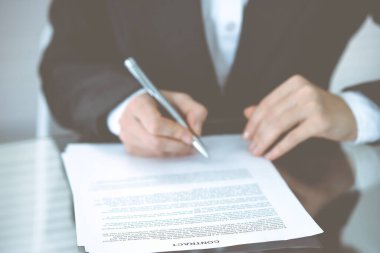 Sözleşme belgesini kalemle teslim eden kimliği belirsiz kadın elleri. Anlaşma imzalama veya iş konsepti