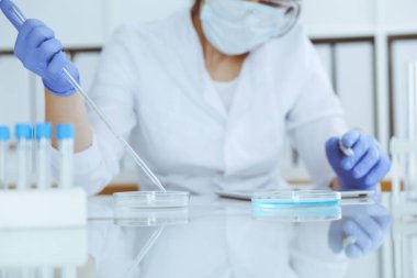 Koruyucu gözlüklü profesyonel kadın bilim adamının laboratuarda reaktörlerle deney yapması. Tıp ve araştırma konsepti